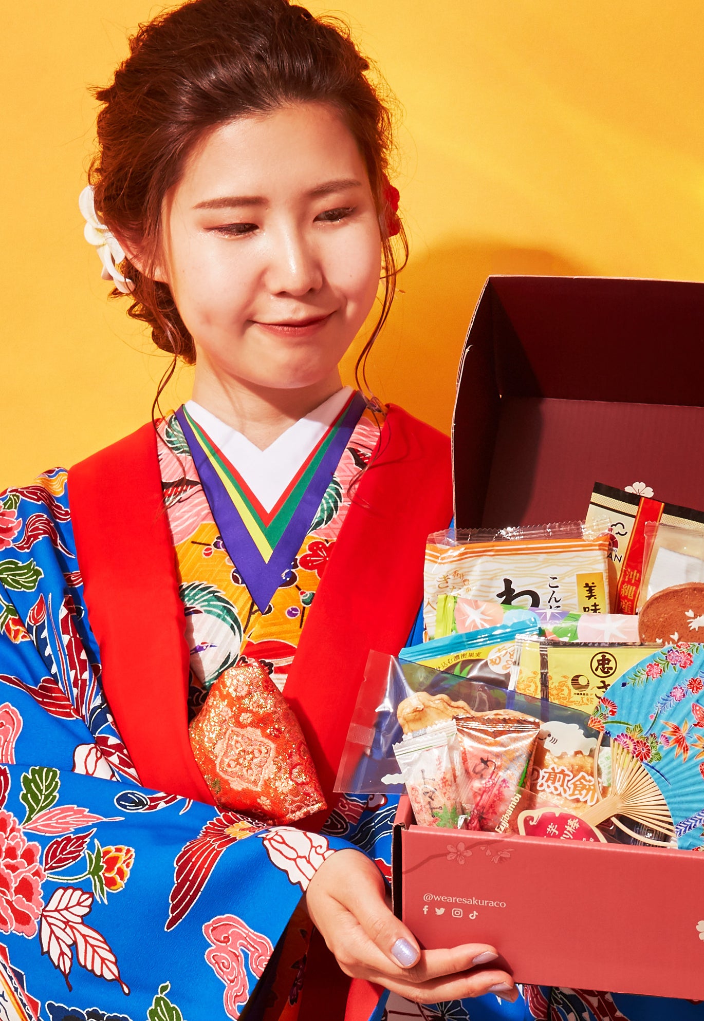 Model holding red box full of Japanese snacks
