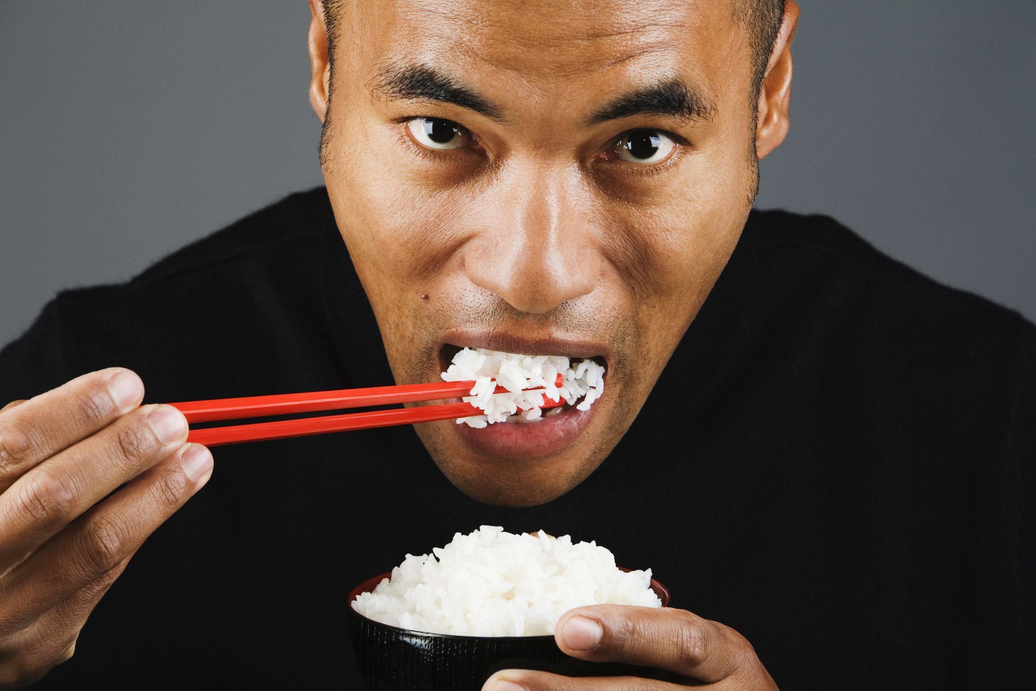 closeup of a man eating white rice with chopsticks
