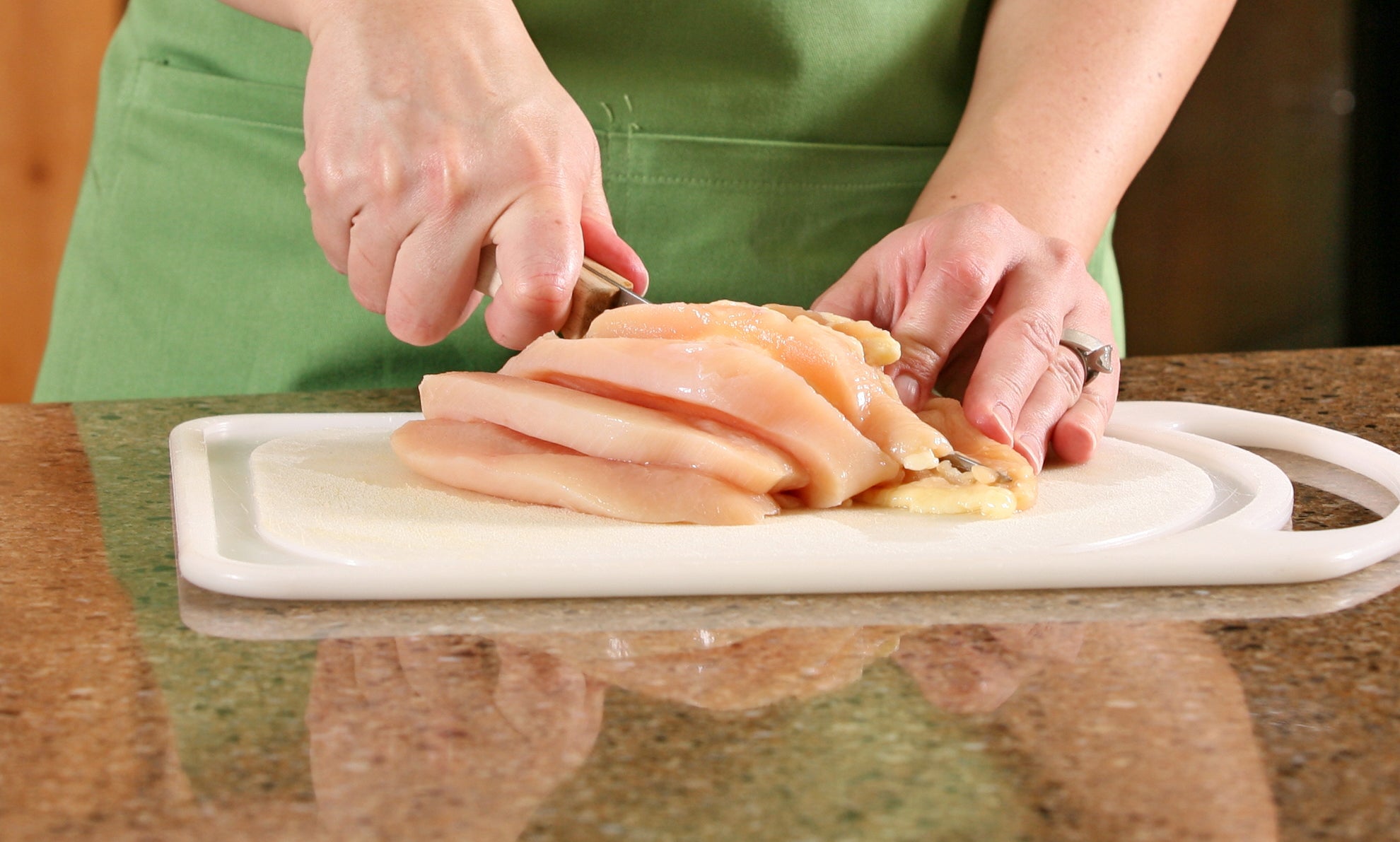 Slicing raw chicken and other ingredients for a meal