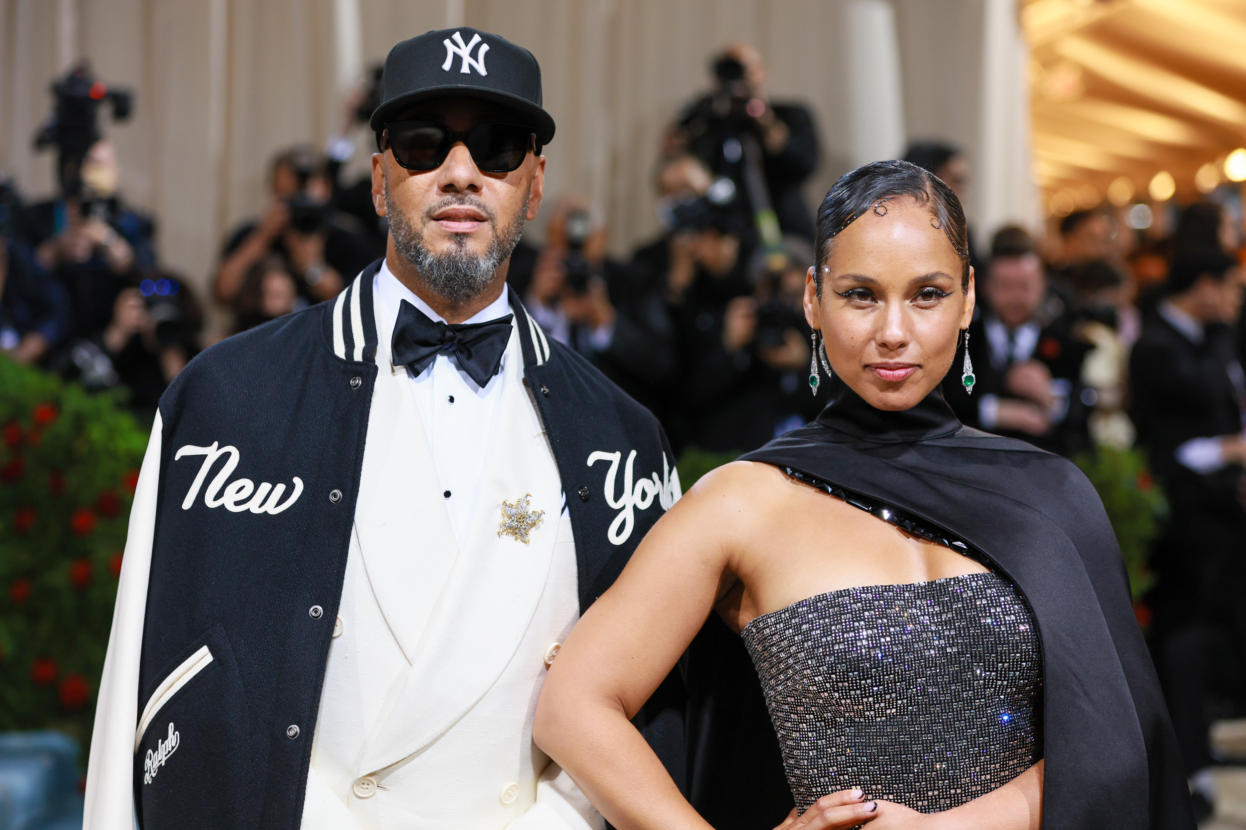 Swizz Beatz in a suit with New York Yankees cap and Alicia in a sparkly dress with a shawl, at an event