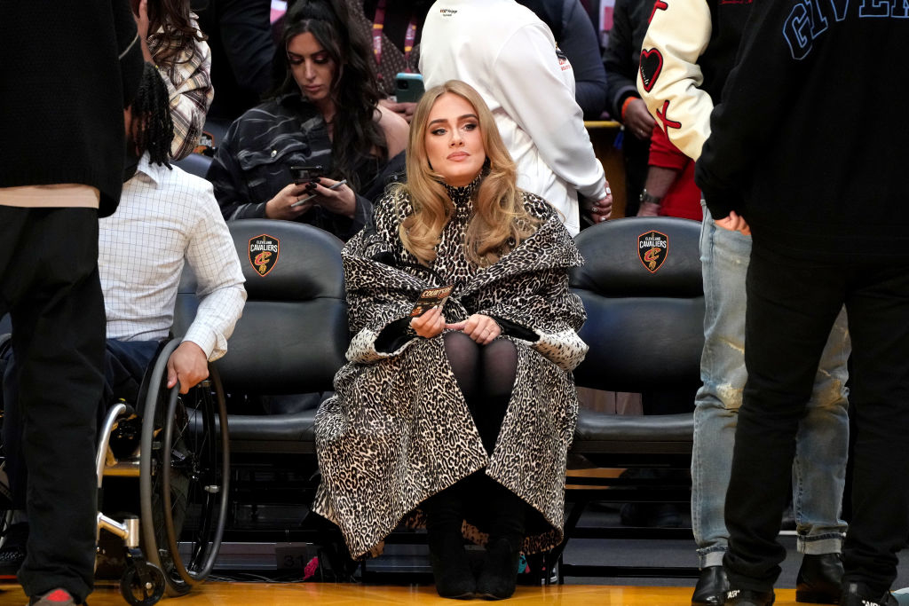 Adele seated at an event wearing a stylish animal print coat