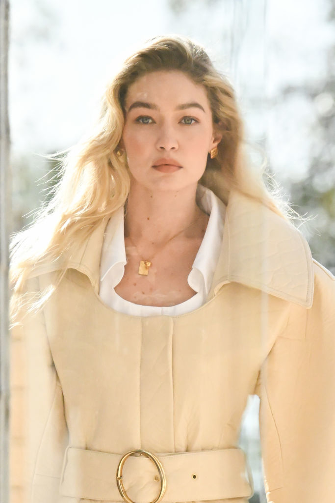 Gigi Hadid in an elegant outfit with a structured collar, accessorized with a large belt and pendant necklace