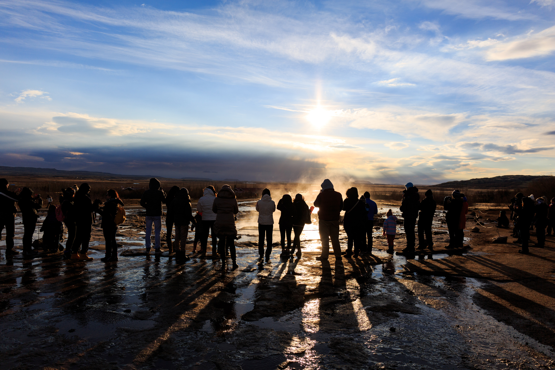 Silhouettes of tourists waiting for the explosion of the Geysir on the Golden Circle in Iceland
