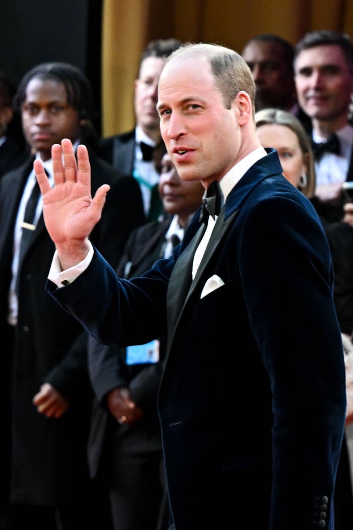 Prince William waving, dressed in a black tuxedo at a formal event