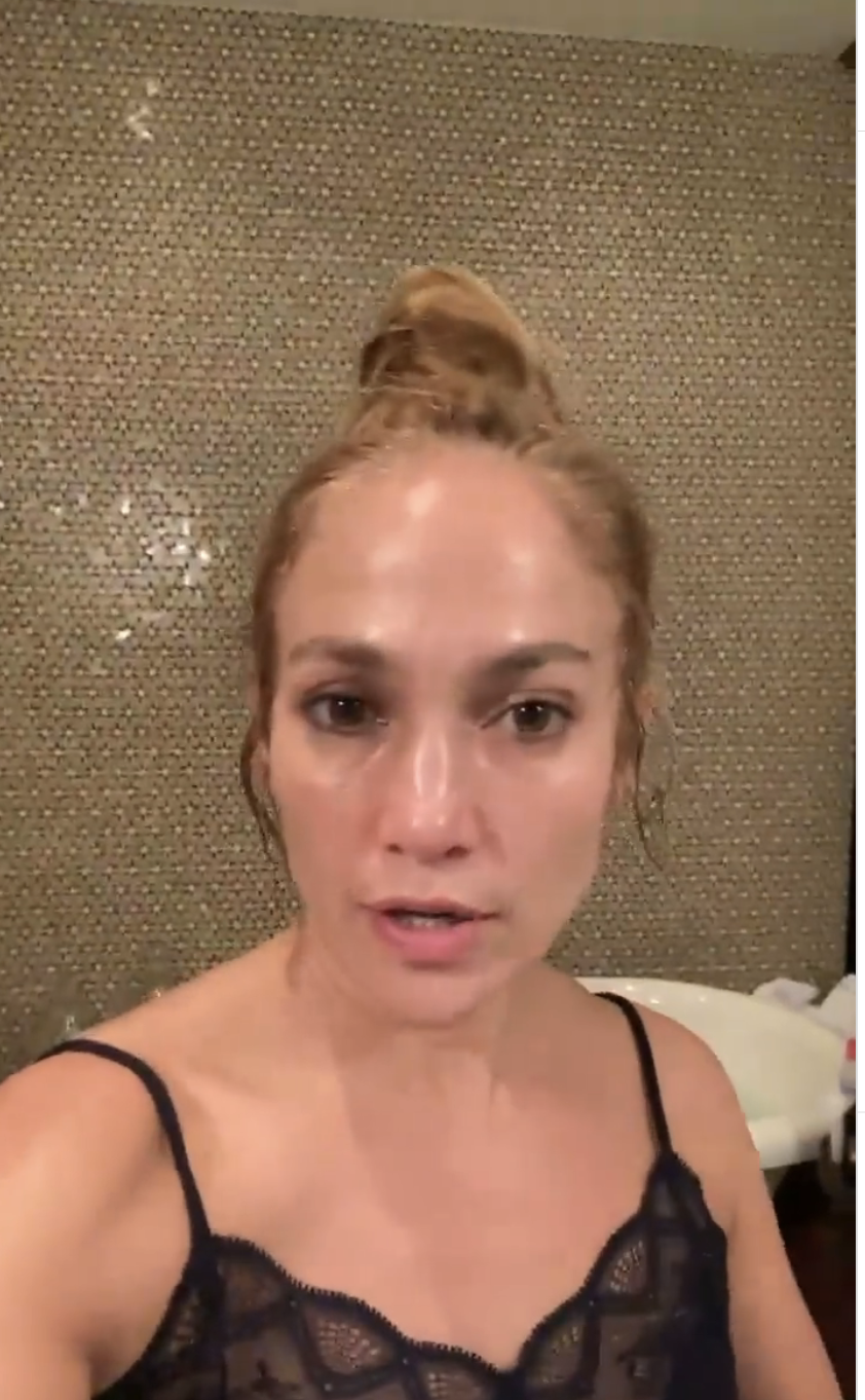 Jennifer Lopez in a casual top with a high bun hairstyle, looks directly into the camera