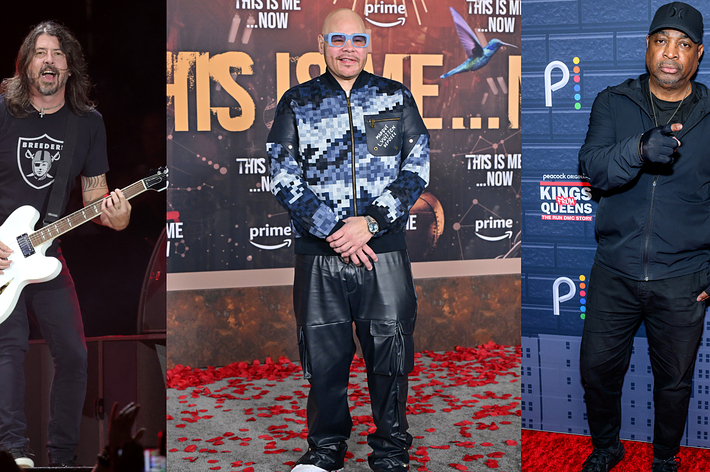 Guitarist performing; two men on red carpet, one in patterned suit, one in casual attire