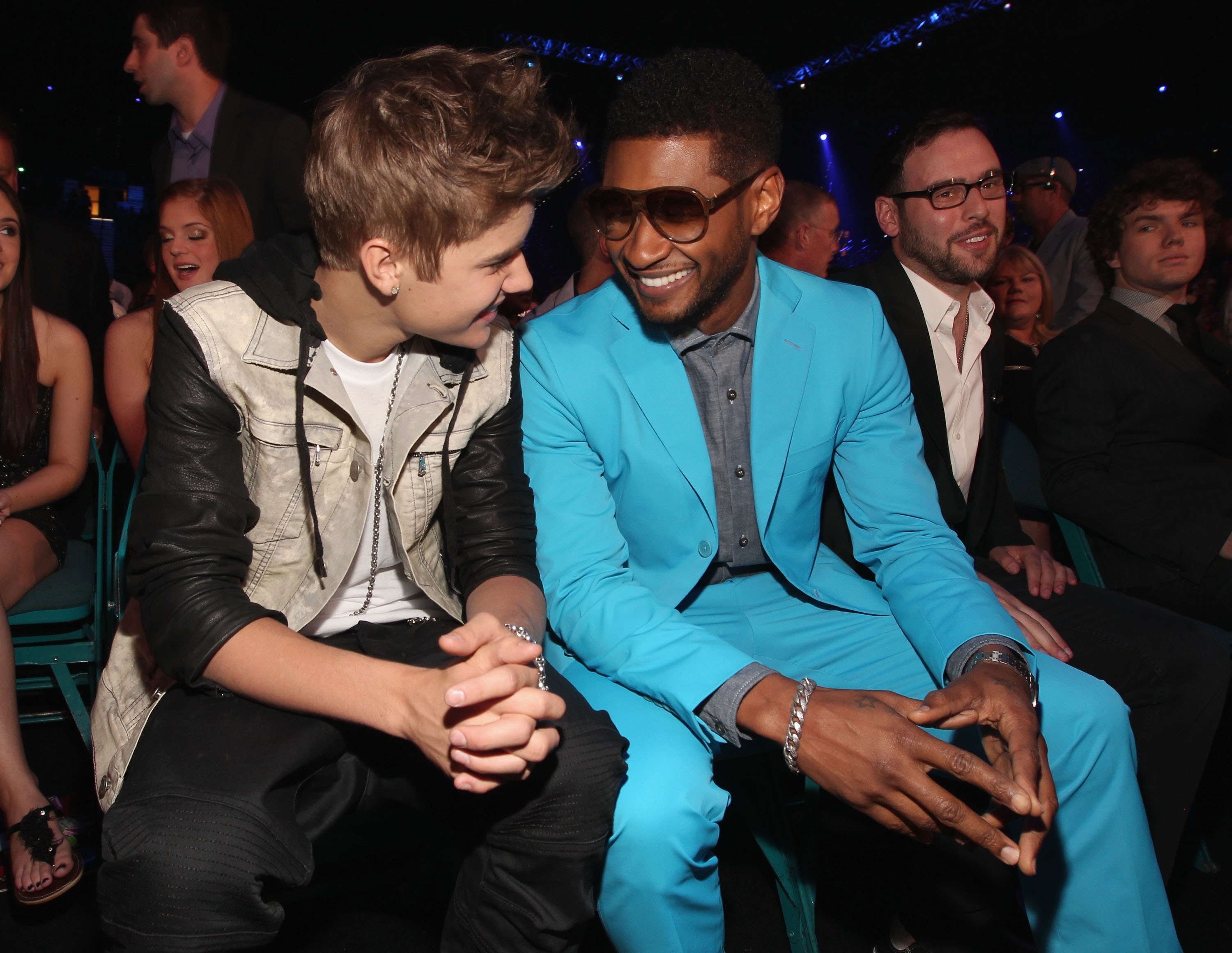 Justin Bieber  seated next to Usher sharing a conversation at an event