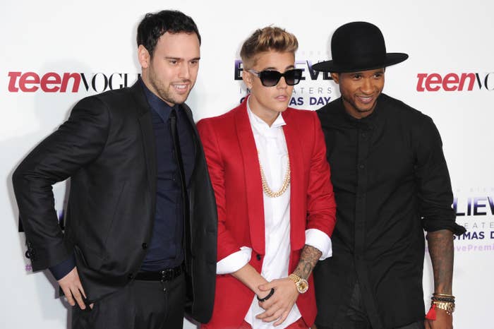 justin standing in between usher and Scooter Braun at an event
