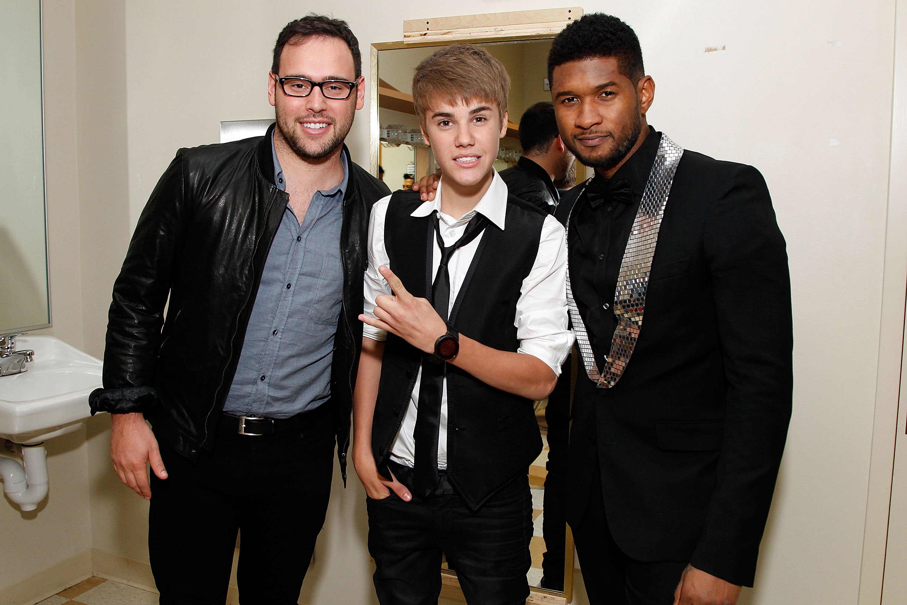 justin standing between scooter and usher in what looks to be a  public bathroom