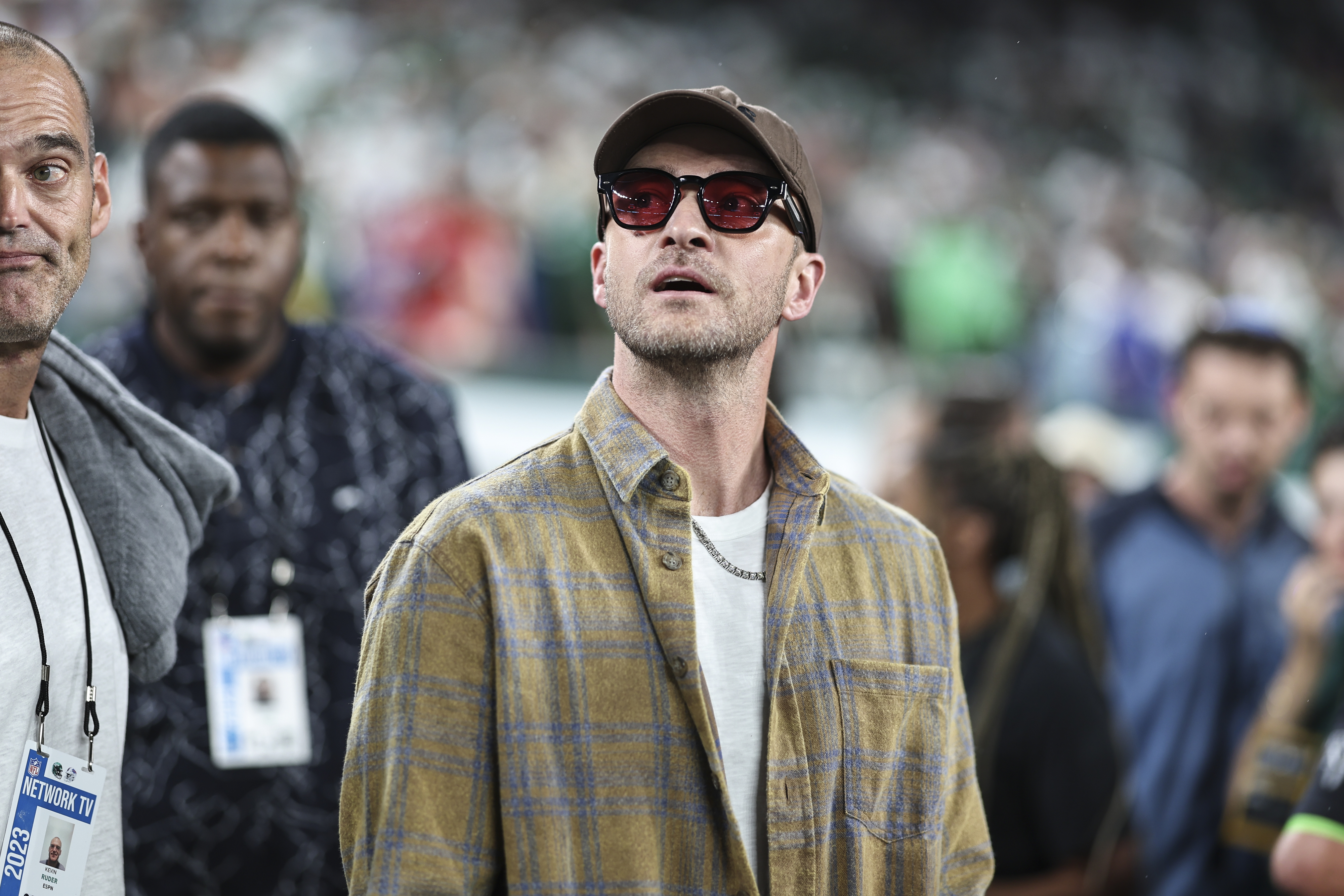 Justin Timberlake wearing a plaid jacket and sunglasses at a sporting event