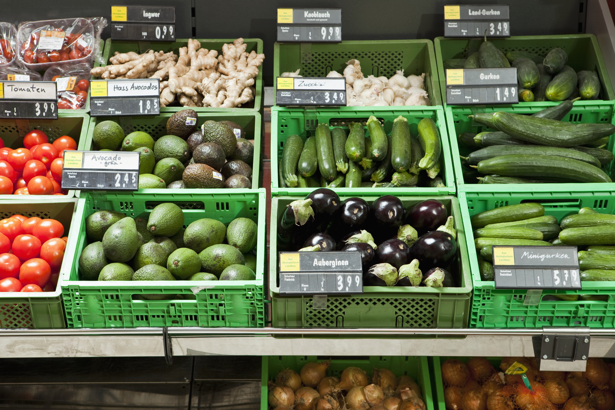 Various fresh vegetables displayed in organized bins at a supermarket