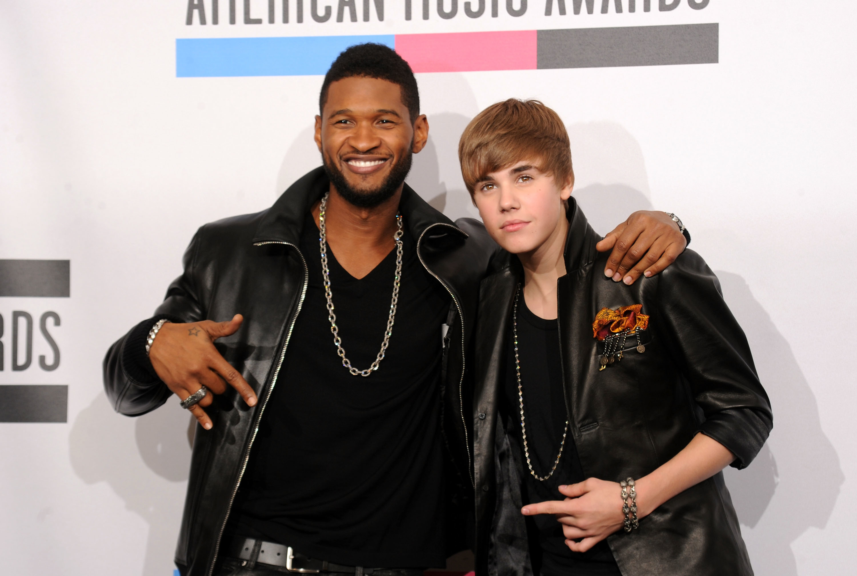 Usher and Justin Bieber posing together at the American Music Awards, both wearing leather jackets