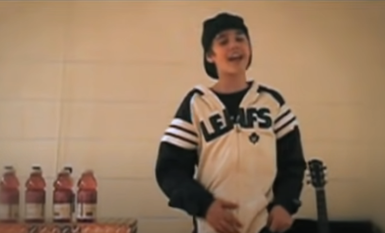 Justin Bieber singing wearing a sports-themed jacket and cap