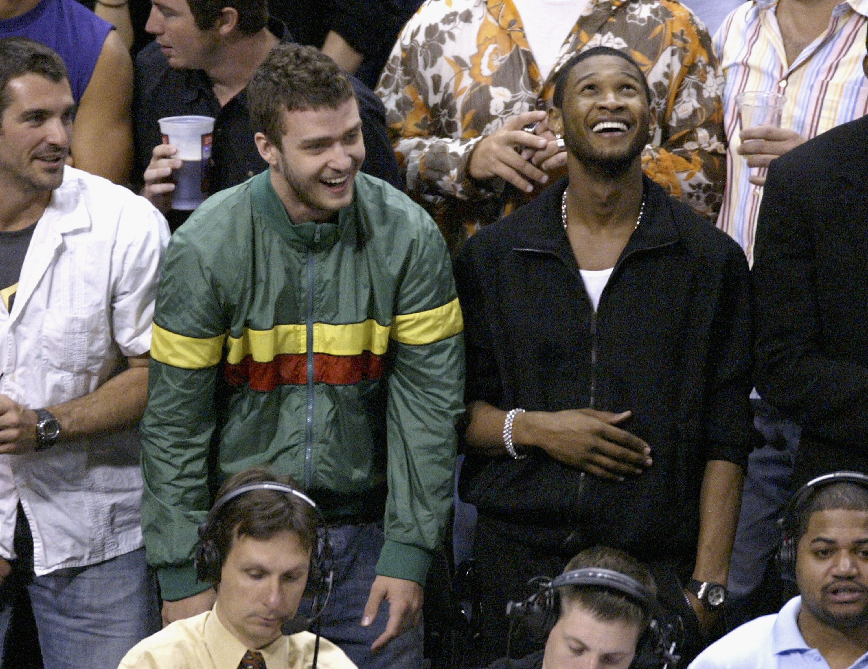 justin timberlake and usher smiling and standing up at a sports event