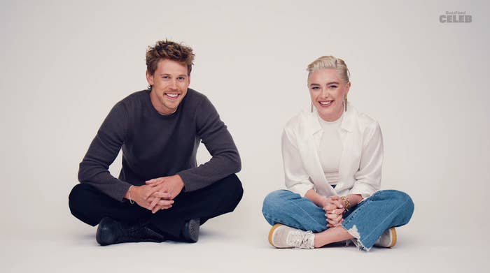 Austin Butler and Florence Pugh seated on the floor, smiling, casual attire, against a white background for an interview