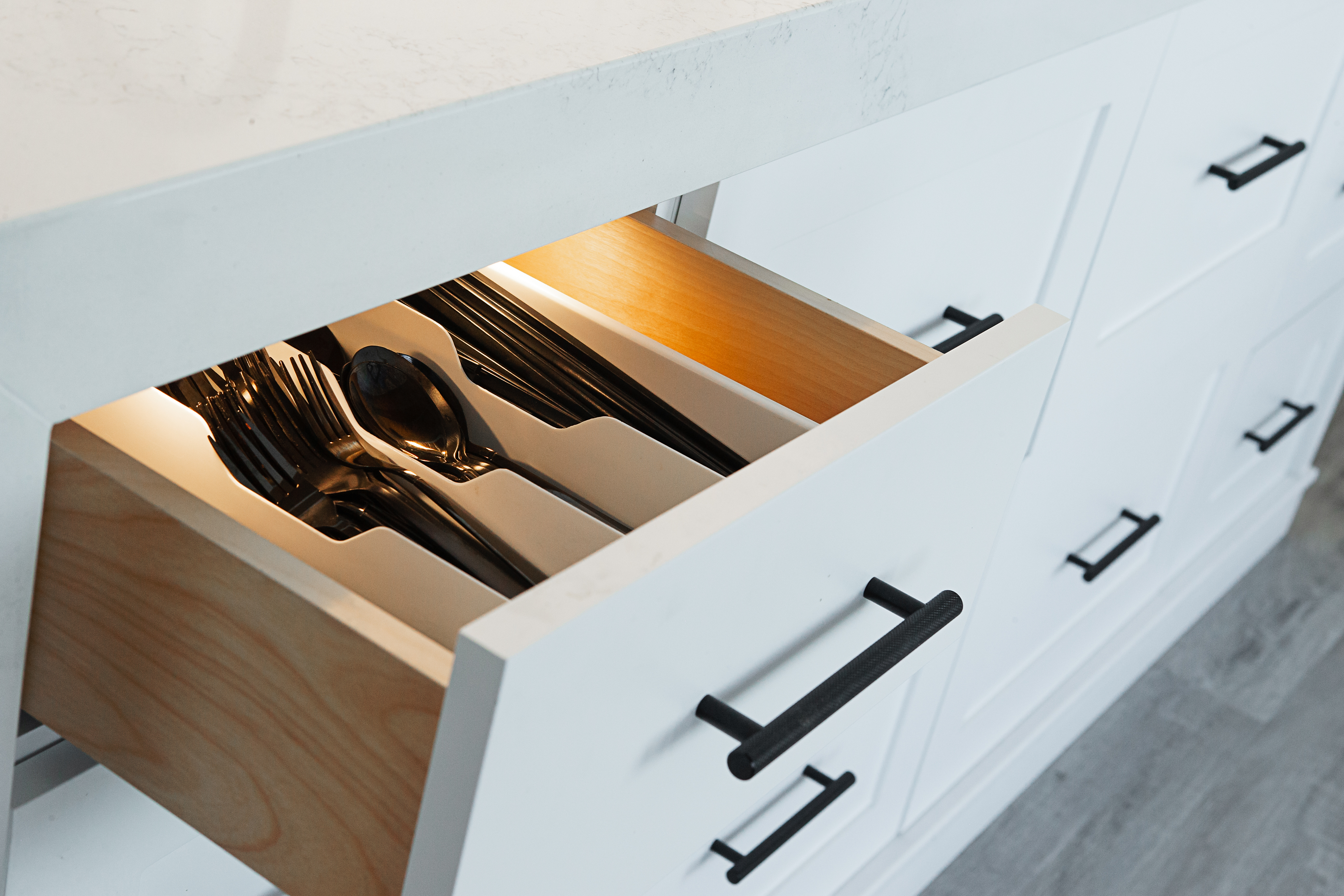 An open kitchen drawer organizing various silverware neatly in compartments