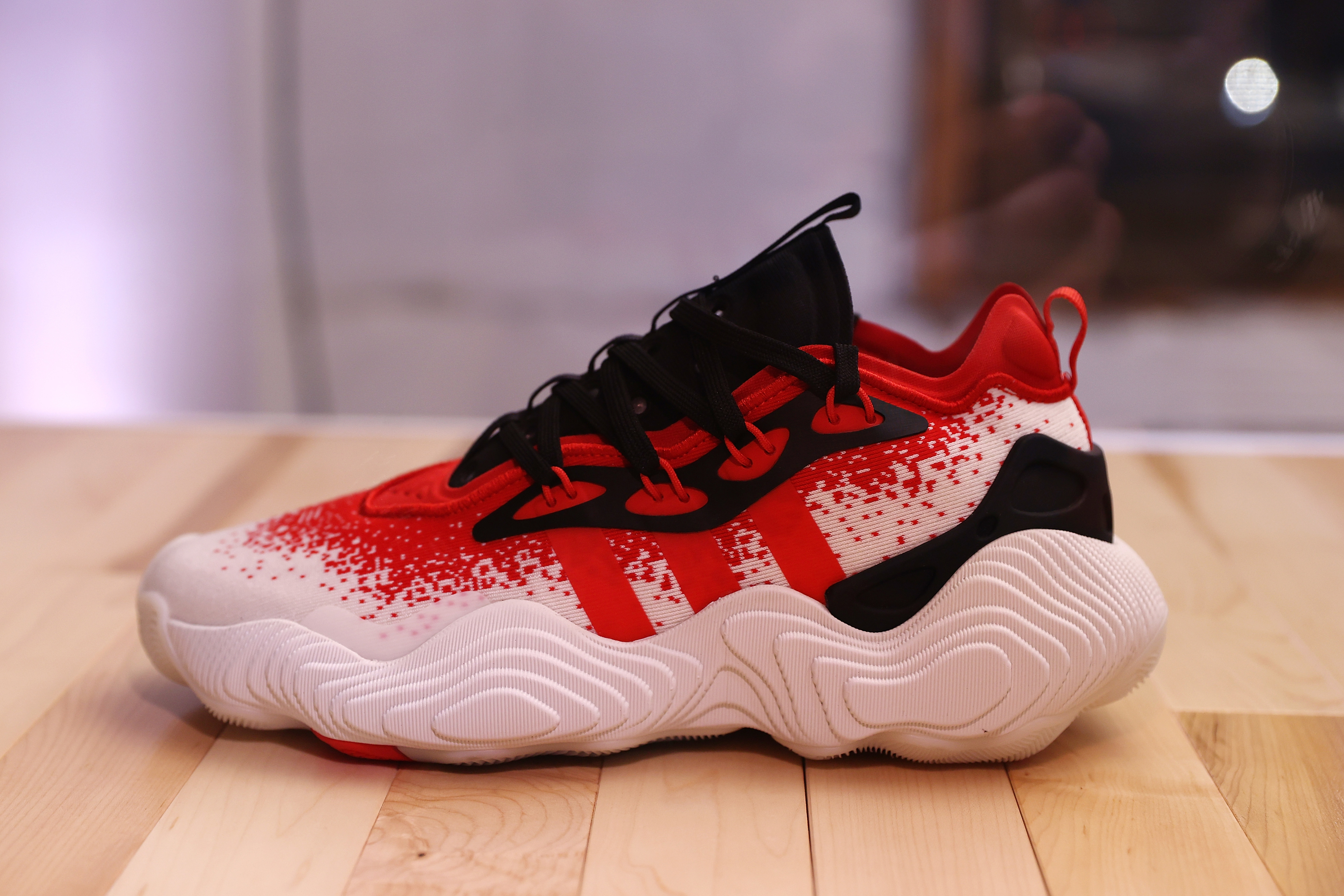 A single white and red splattered sport shoe on a wooden surface
