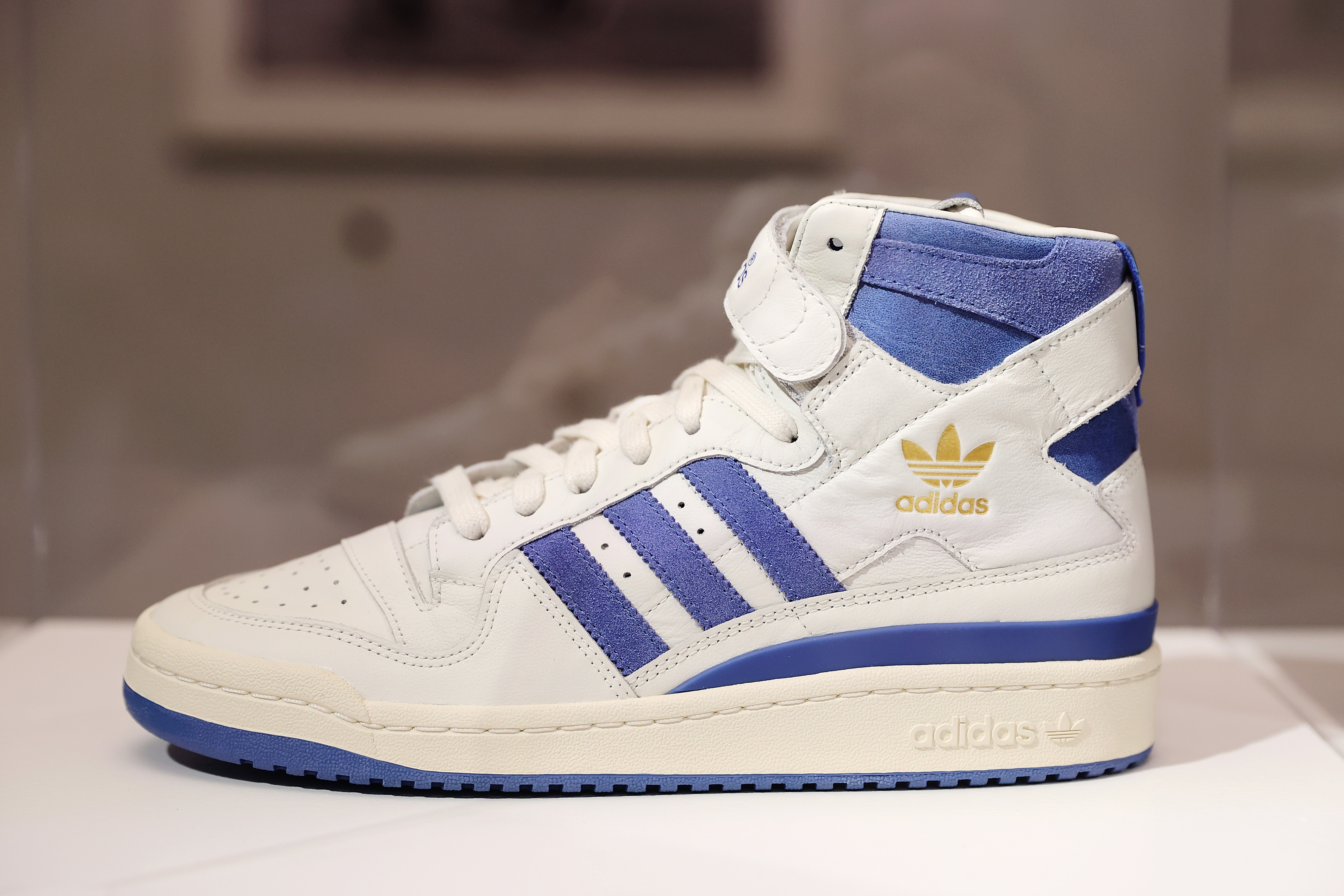 White and blue Adidas high-top sneaker on display