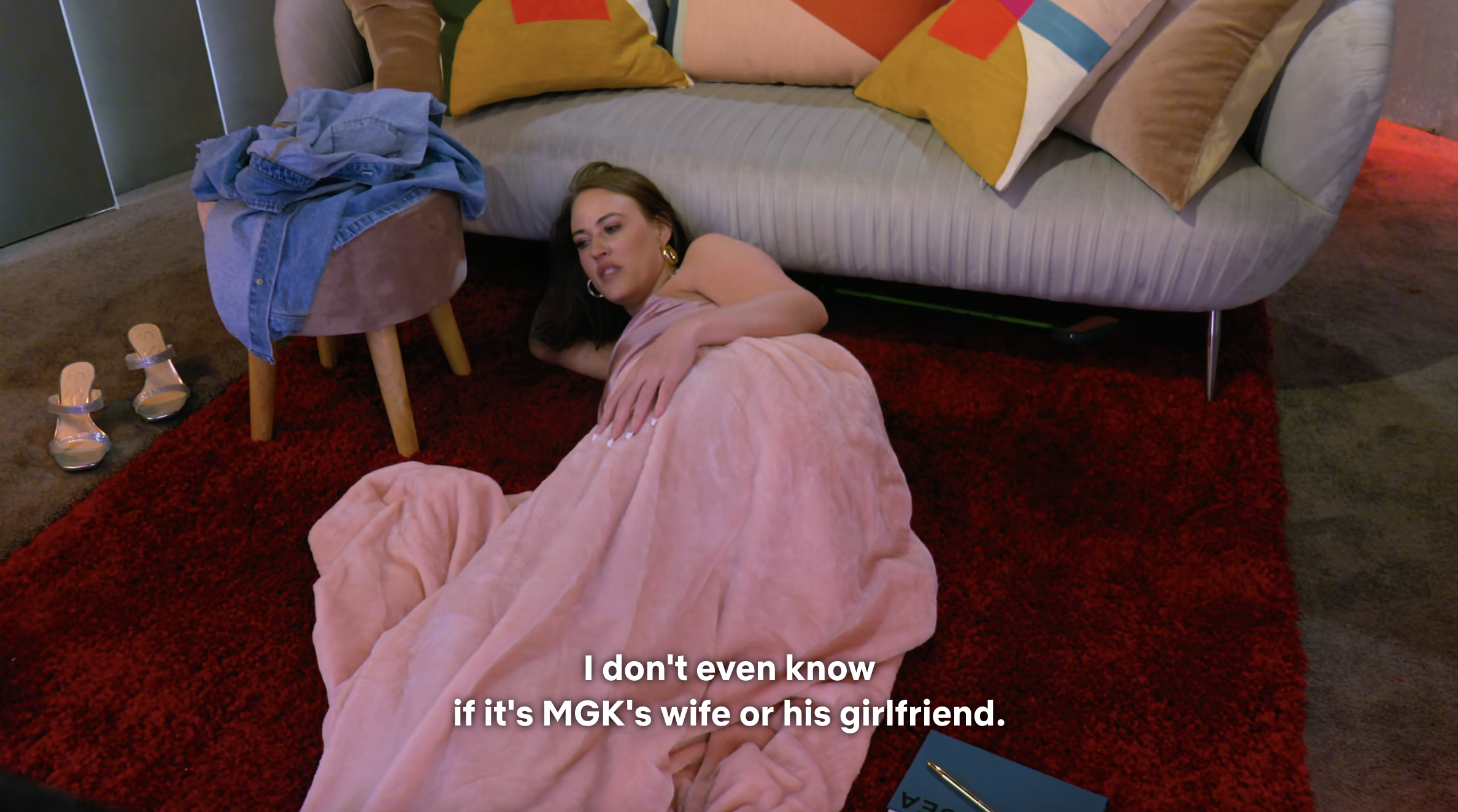 Person in a pink gown lying on a couch with a subtitle about MGK&#x27;s relationship status