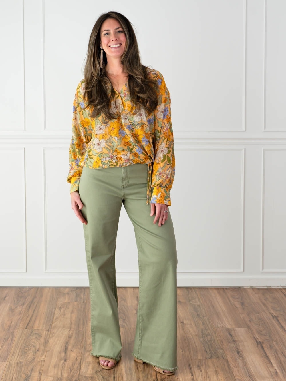 Woman in floral blouse and green trousers, standing with a smile, ideal for a shopping category