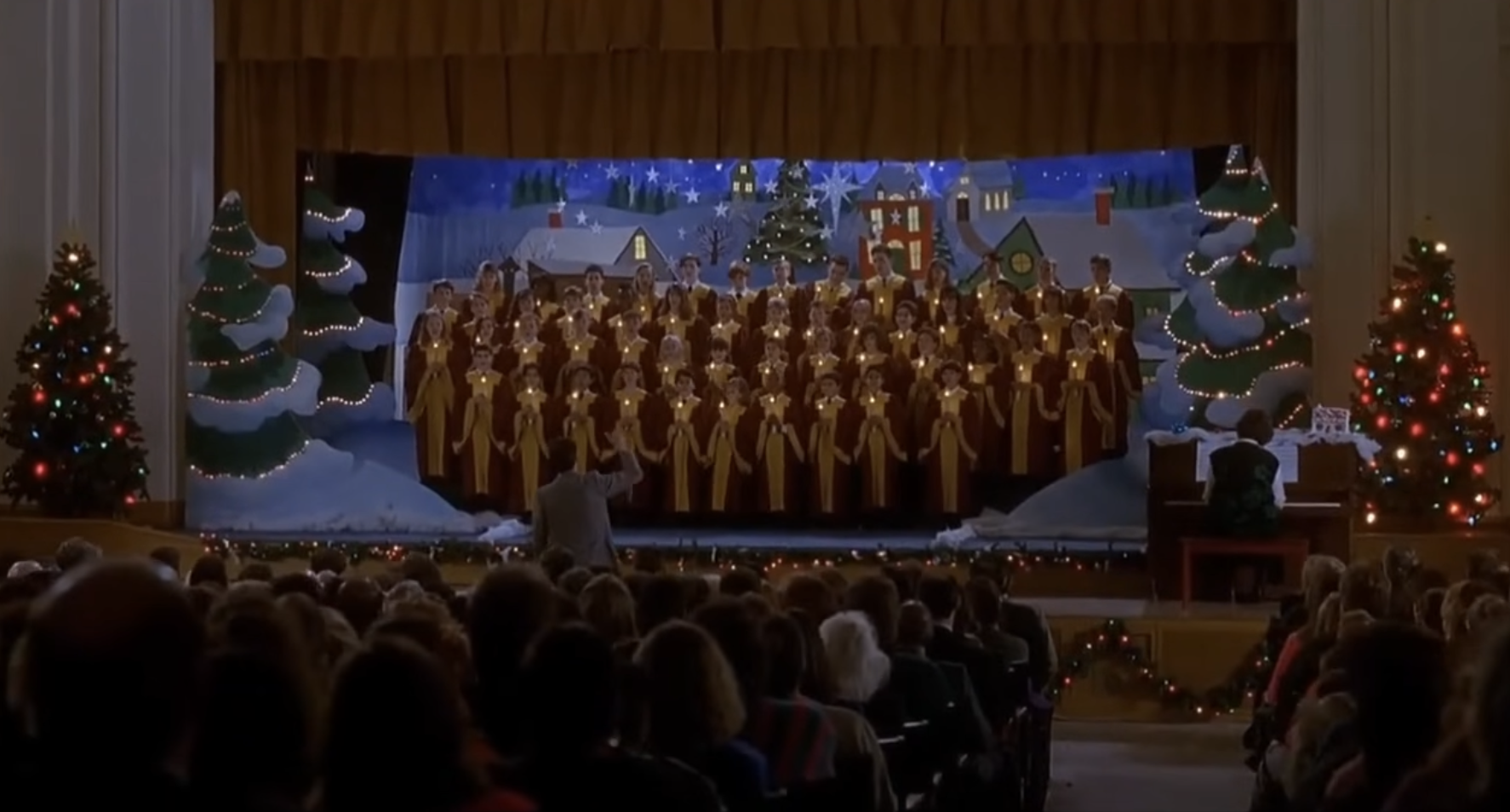 Children&#x27;s choir onstage in a festive setup with audience in foreground