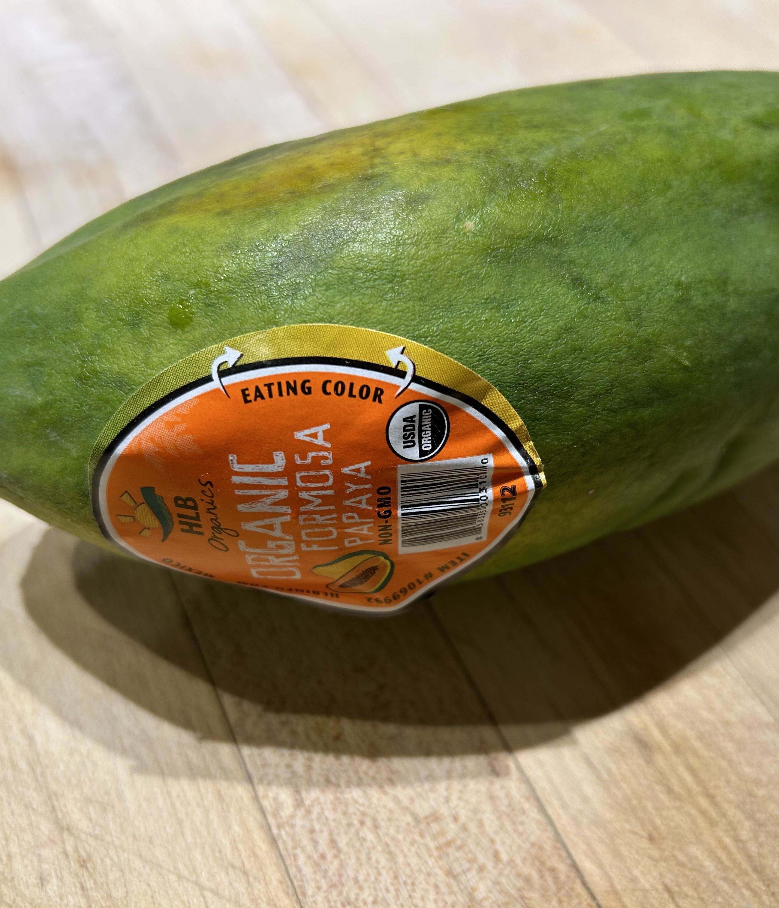 Sticker on a papaya with text &quot;EATING COLOR Organic UGLYFRUIT&quot; to promote produce