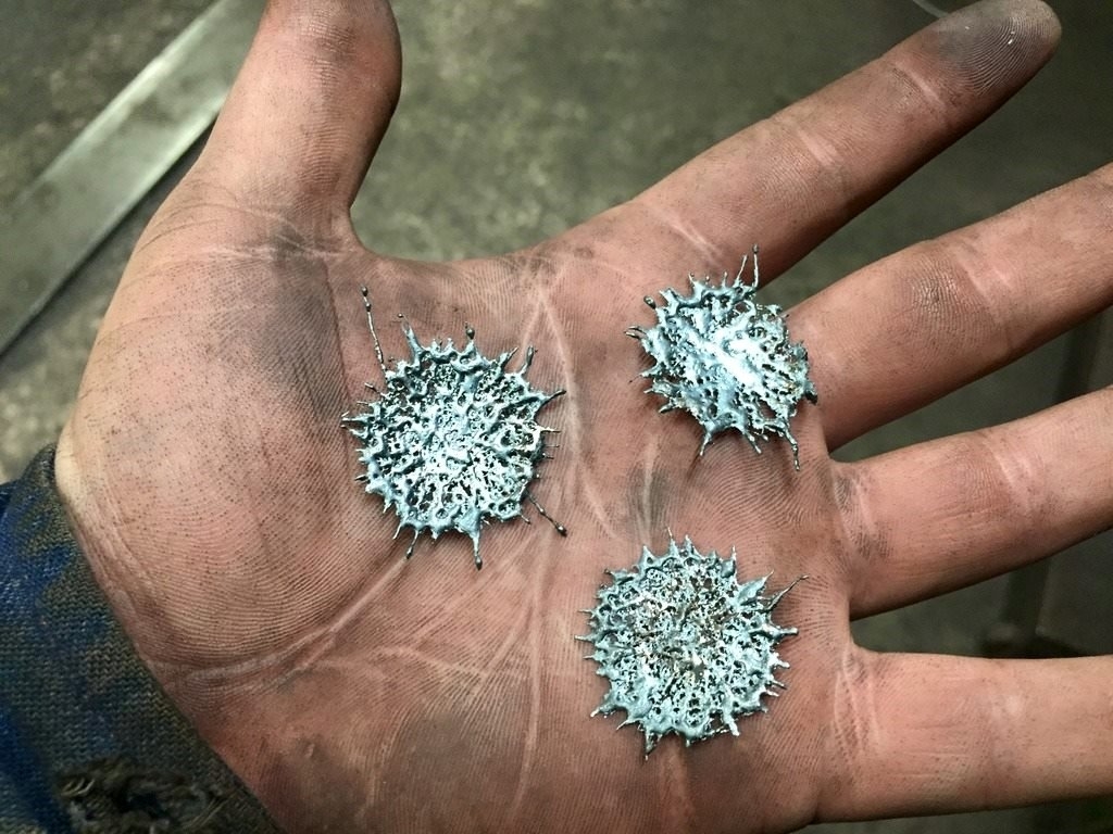 Open hand holding three magnetic metal shavings clusters with spiked patterns