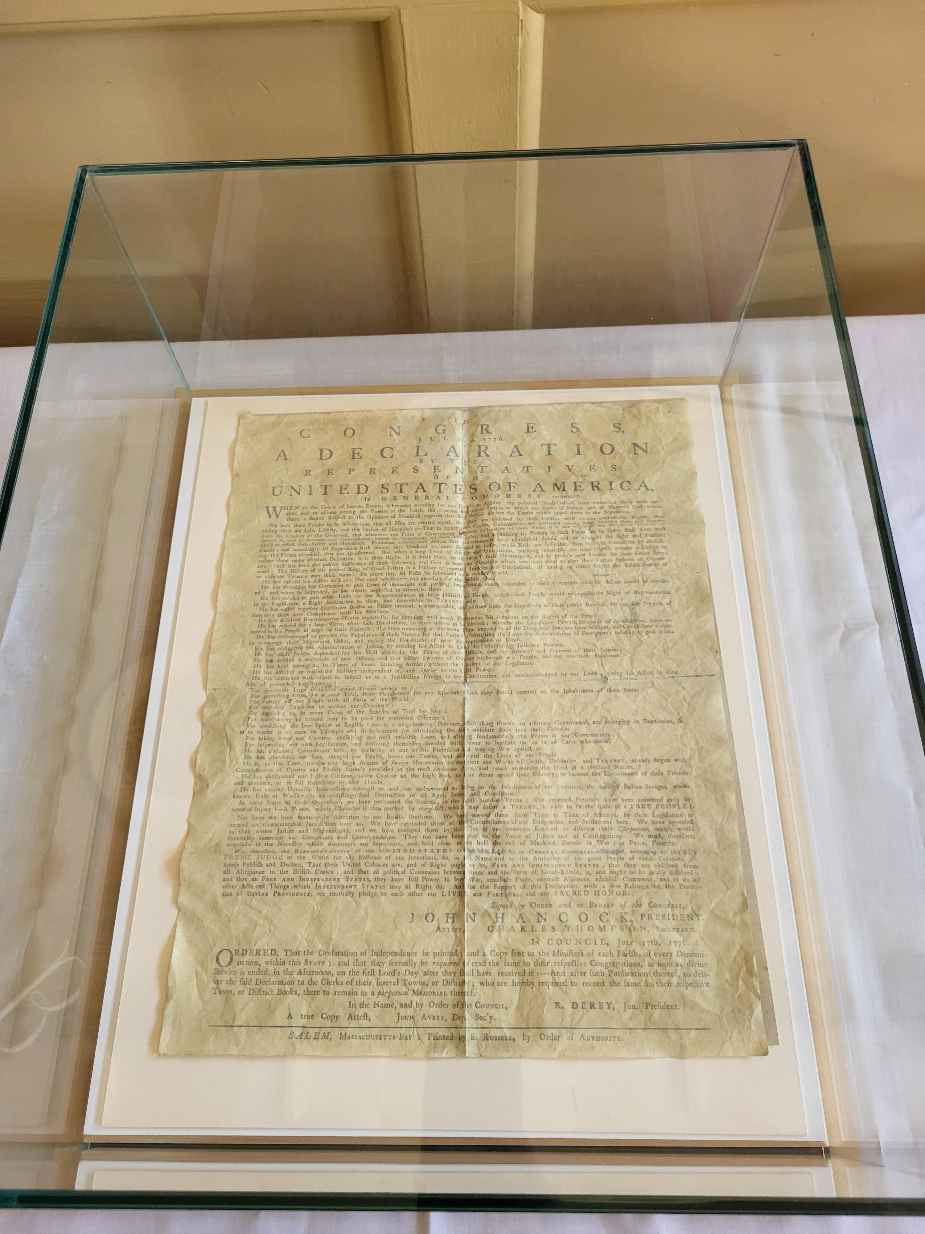 Historical document, presumed to be the Declaration of Independence, displayed under glass