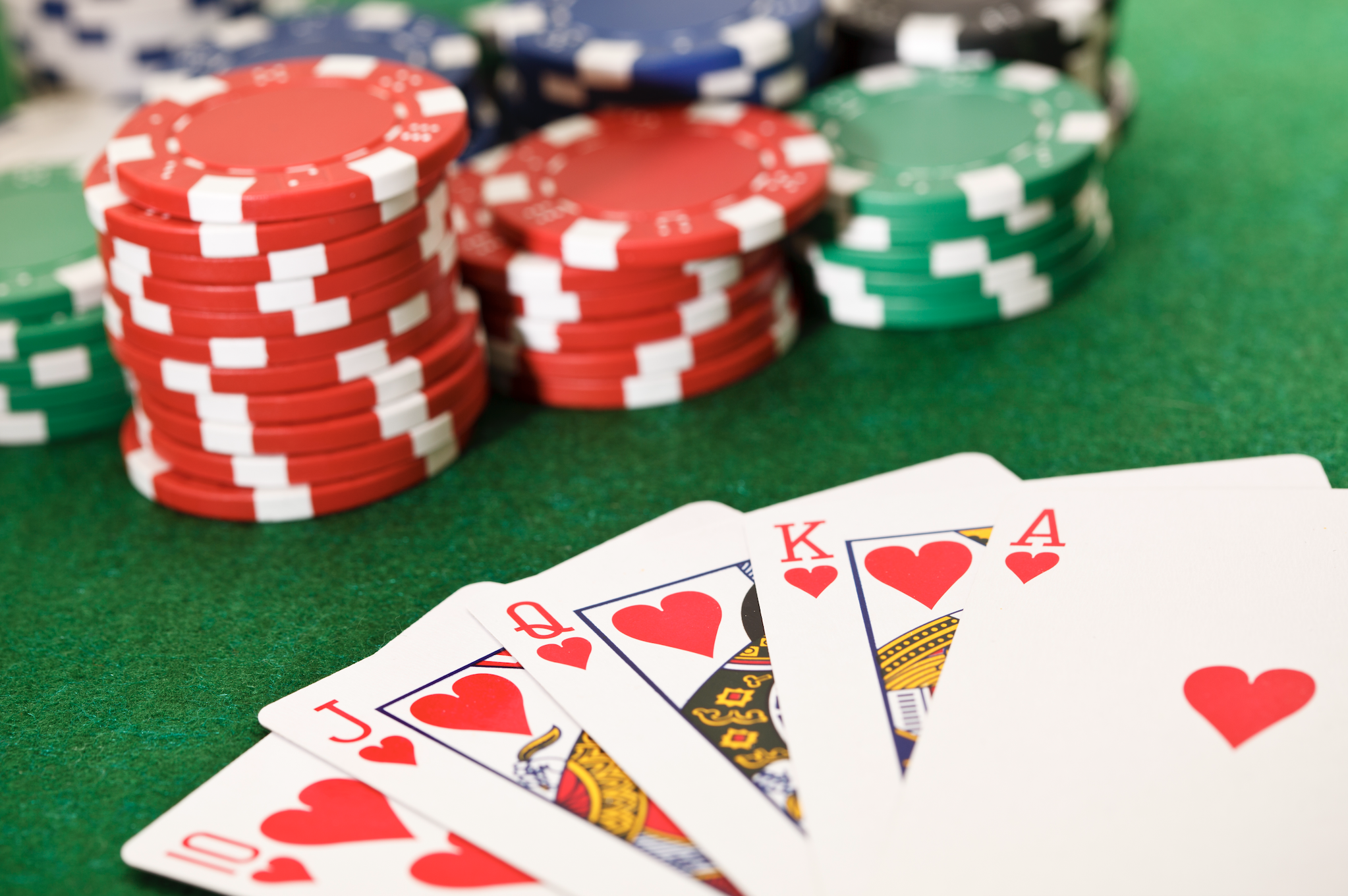 Poker hand with royal flush alongside poker chips on a table, implying financial risk and reward in gaming