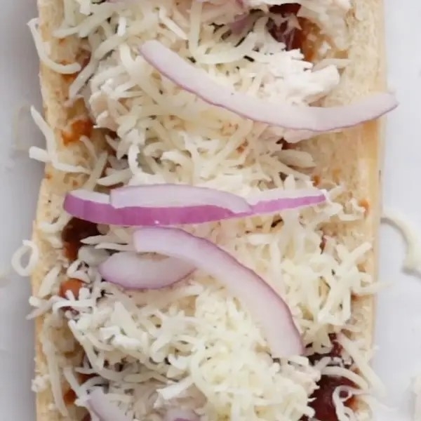 Open sandwich with shredded cheese and onion slices on top