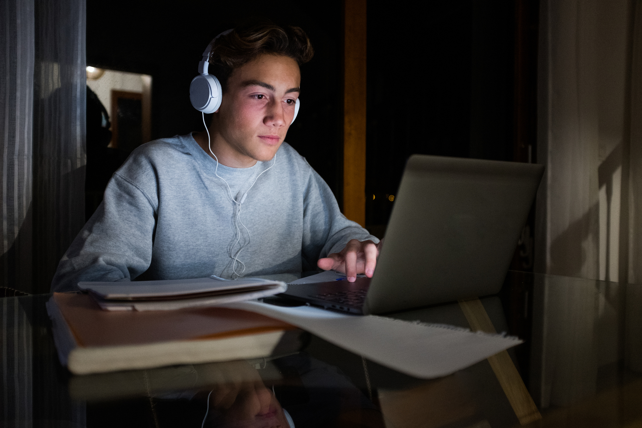 Teenager using his laptop to do homework and listen to music at night