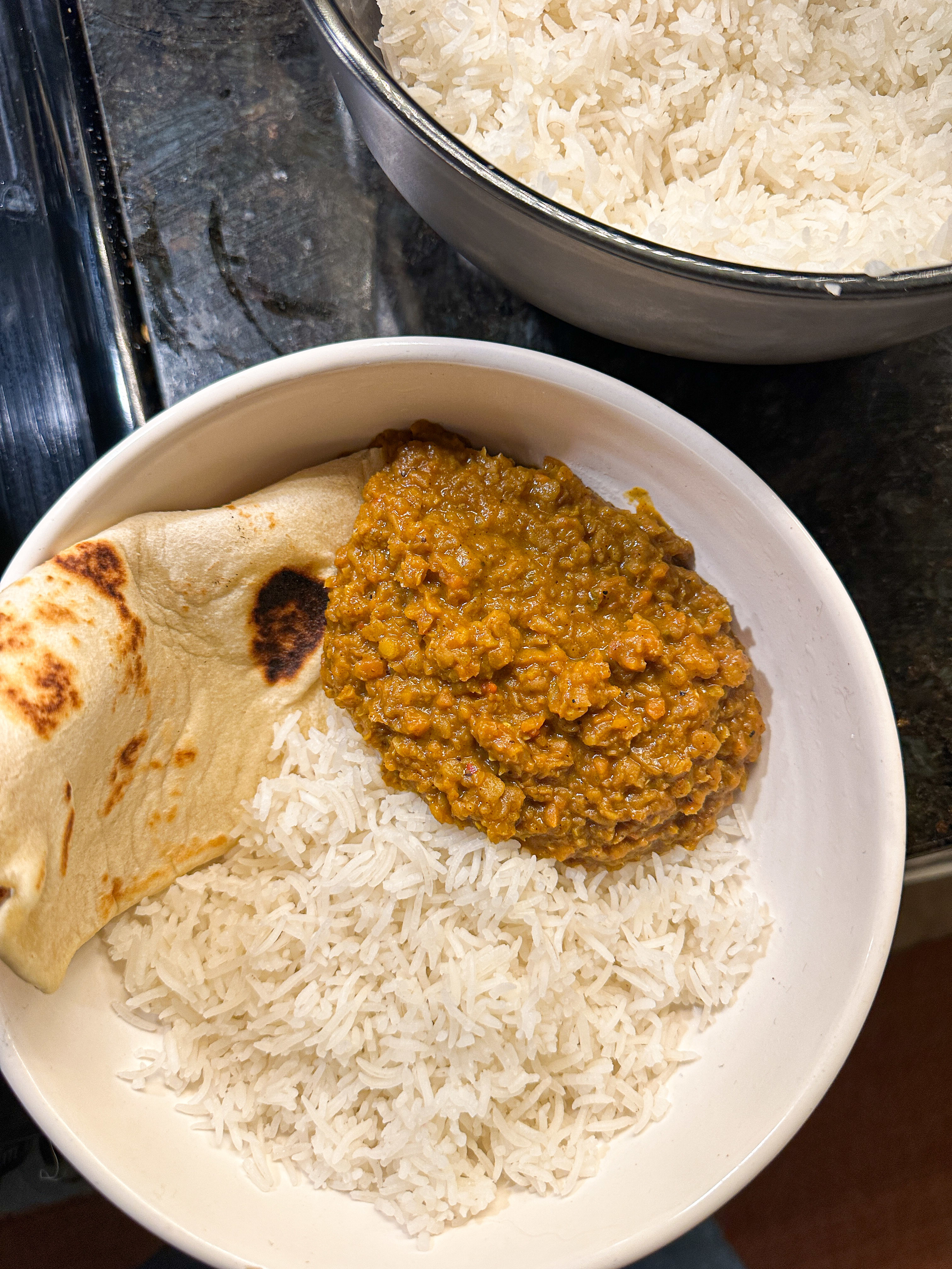Bowl of rice with lentil curry and a side of naan bread