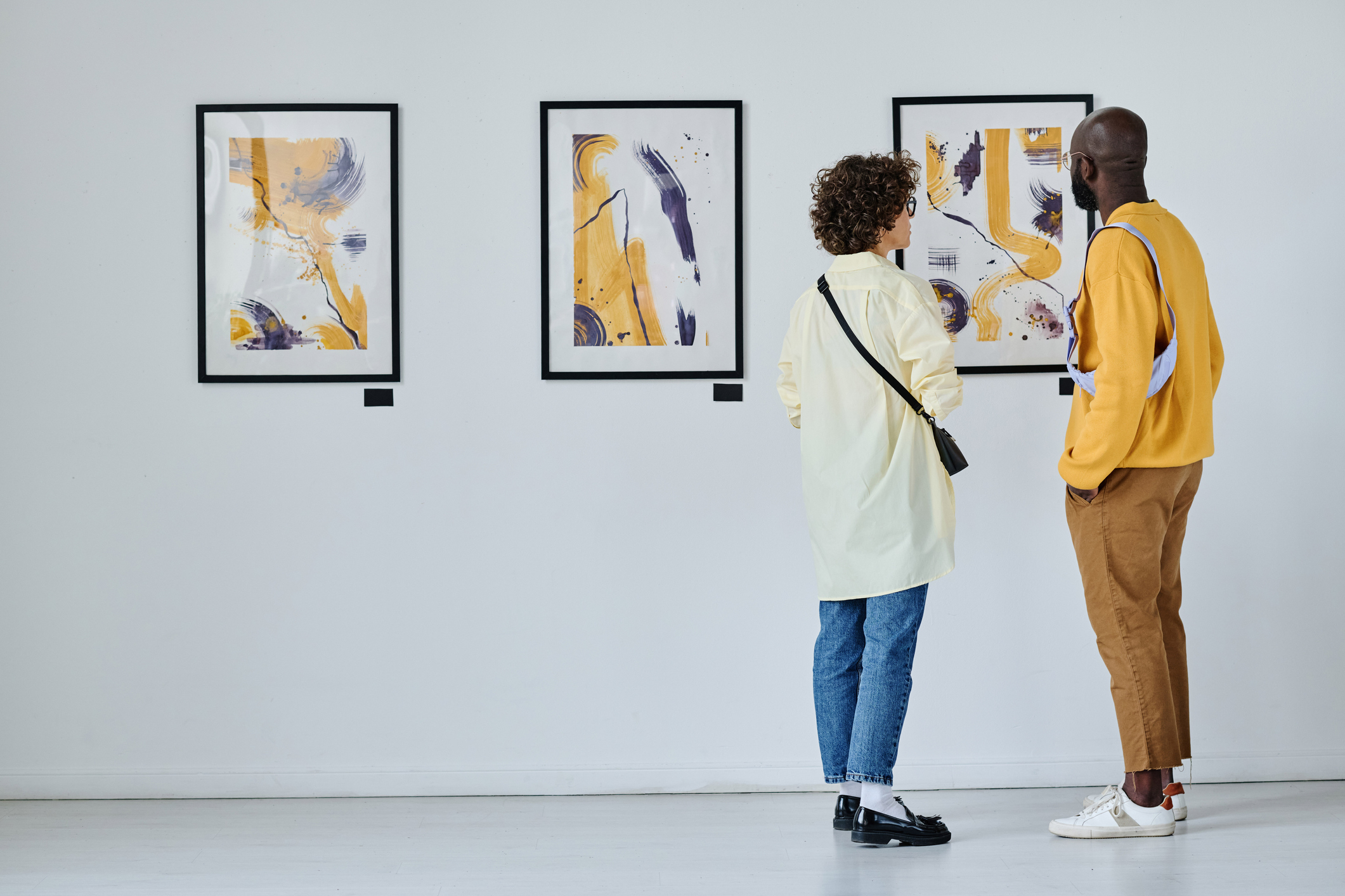 Two people viewing abstract art in a gallery