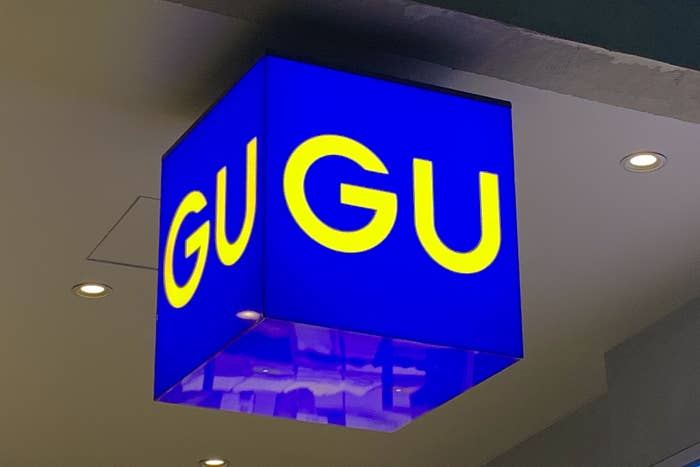 Illuminated sign with the text &quot;GU GU&quot; on a blue background, hanging from a ceiling