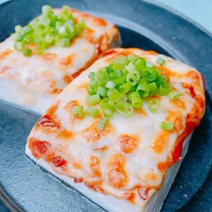 焼きチーズがのった豆腐が二切れあり、刻んだネギが上に散らされています。