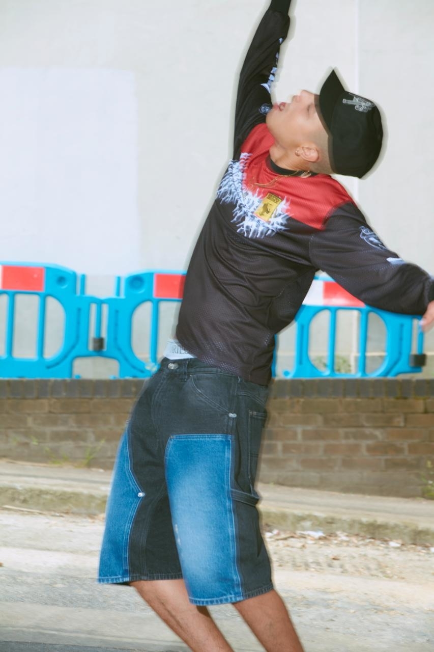 Individual in a cowboy hat and graphic shirt playing a tossing game outdoors
