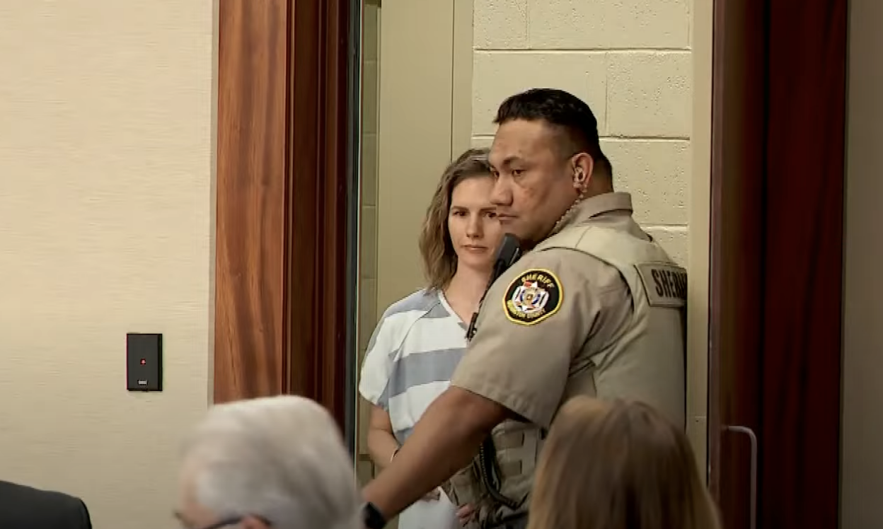 ruby walking into the court room, escorted by a cop