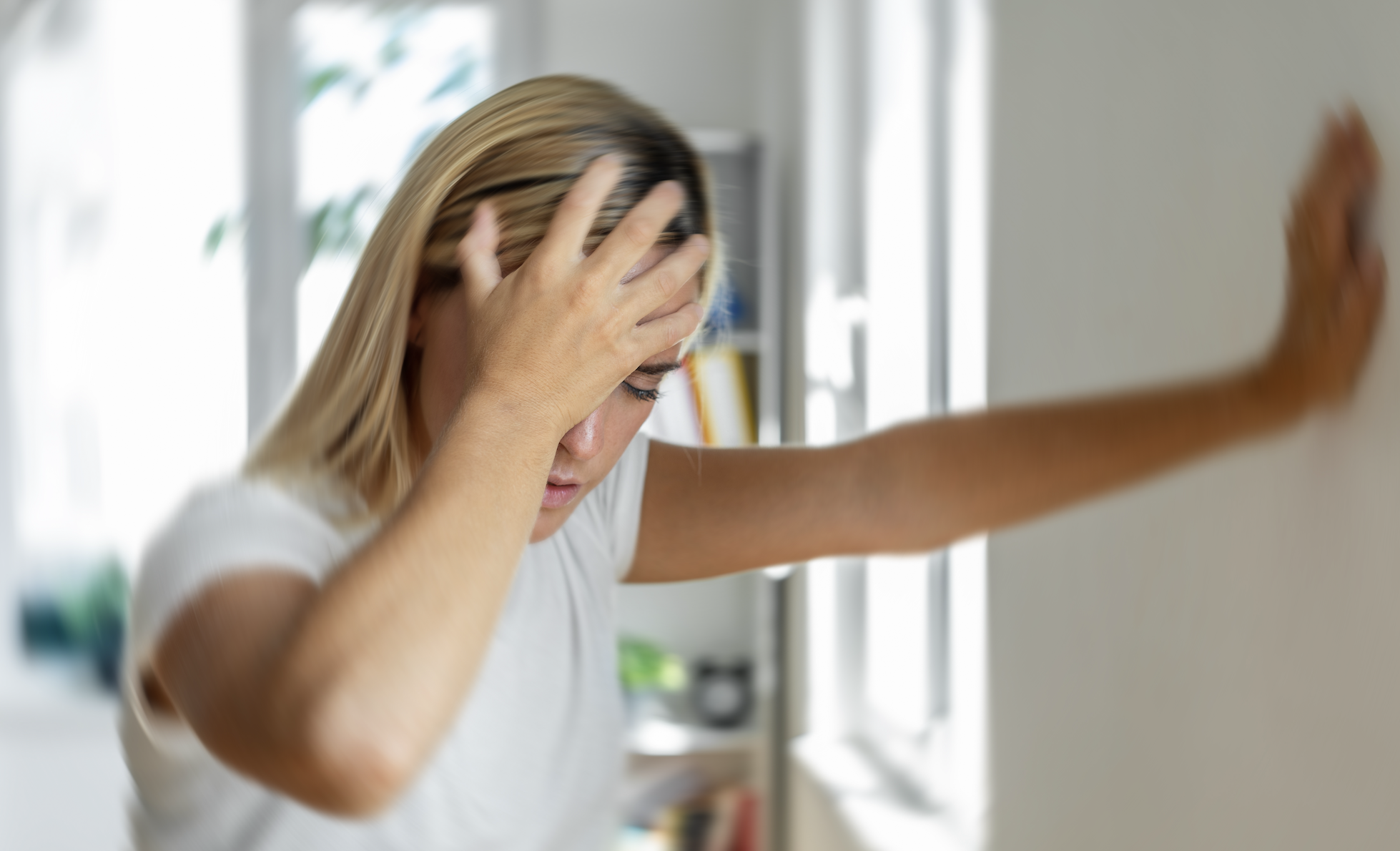 Person looking stressed with hands on head near a window, conveying emotion for a wellness article