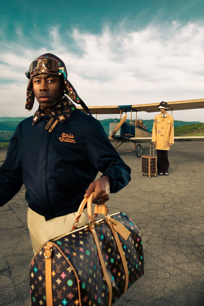 Tyler in a Louis Vuitton hoodie and scarf holds branded bag