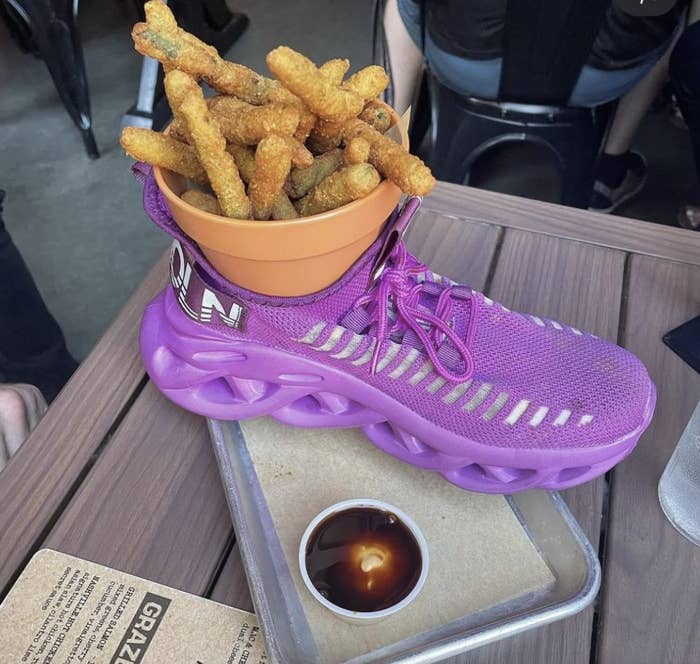 Sneaker serving bowl with a pot filled with fries on a tray with dipping sauce; quirky food presentation