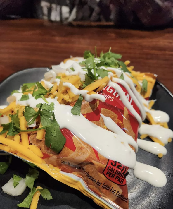 A bag of Fritos topped with cheese, sour cream, and cilantro