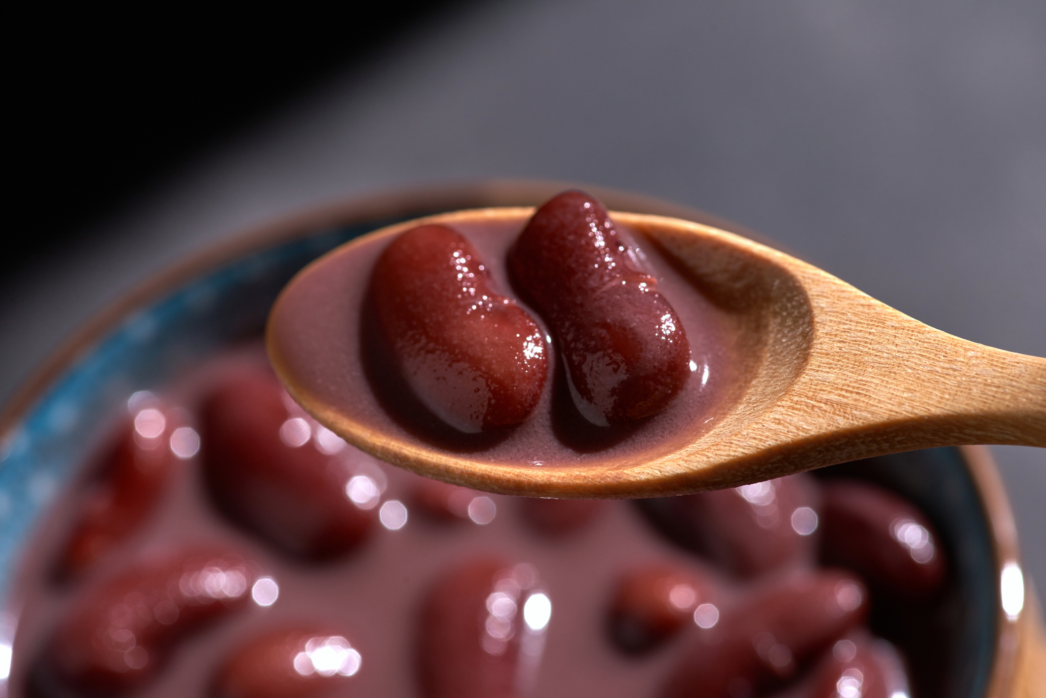 Wooden spoon holding kidney beans over a bowl of bean soup