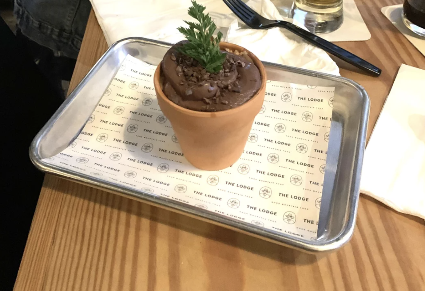 Dessert in a flowerpot on a tray on a wooden table