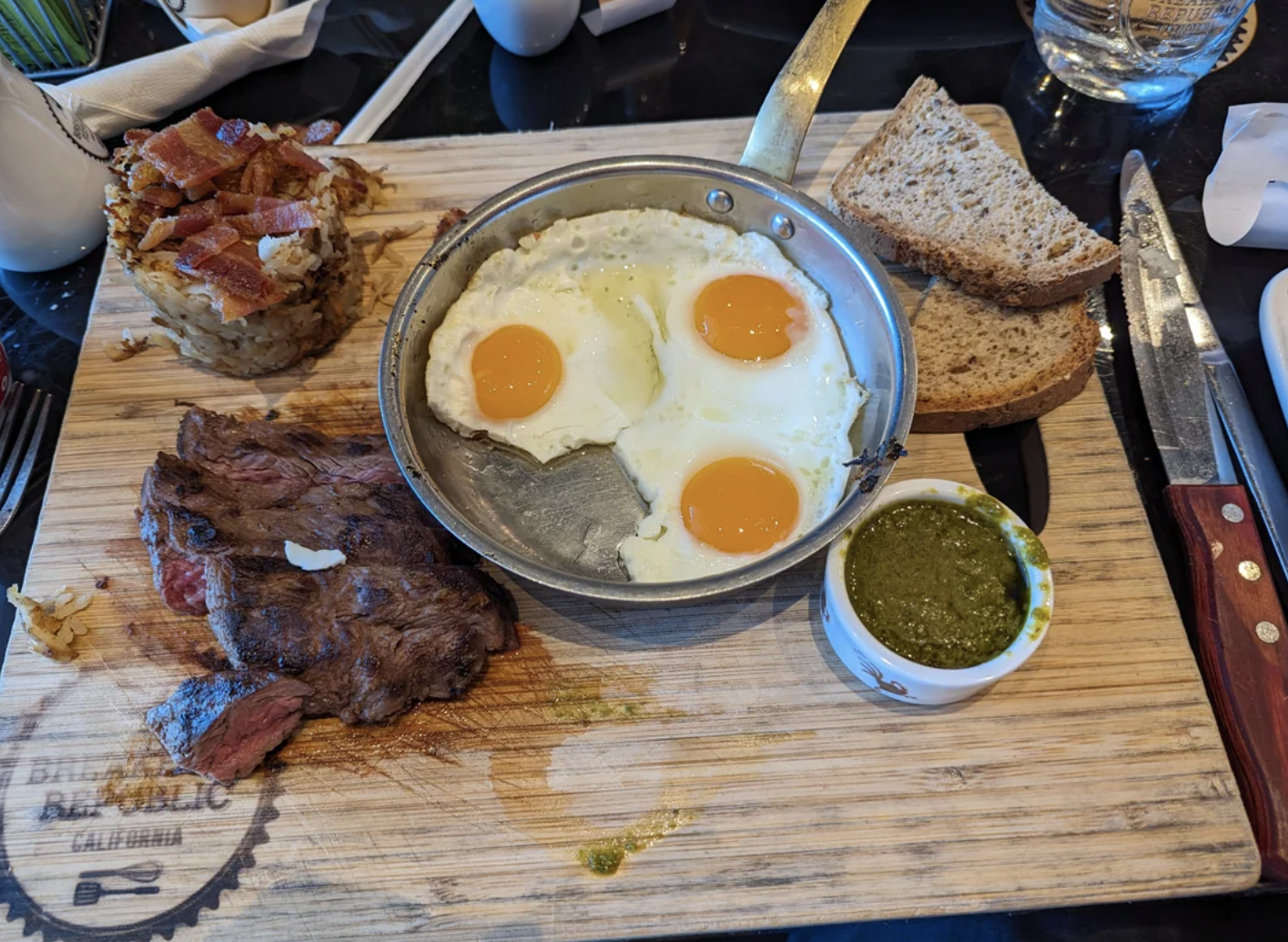 Hearty breakfast of eggs, steak, toast, and hash with condiments on a restaurant table