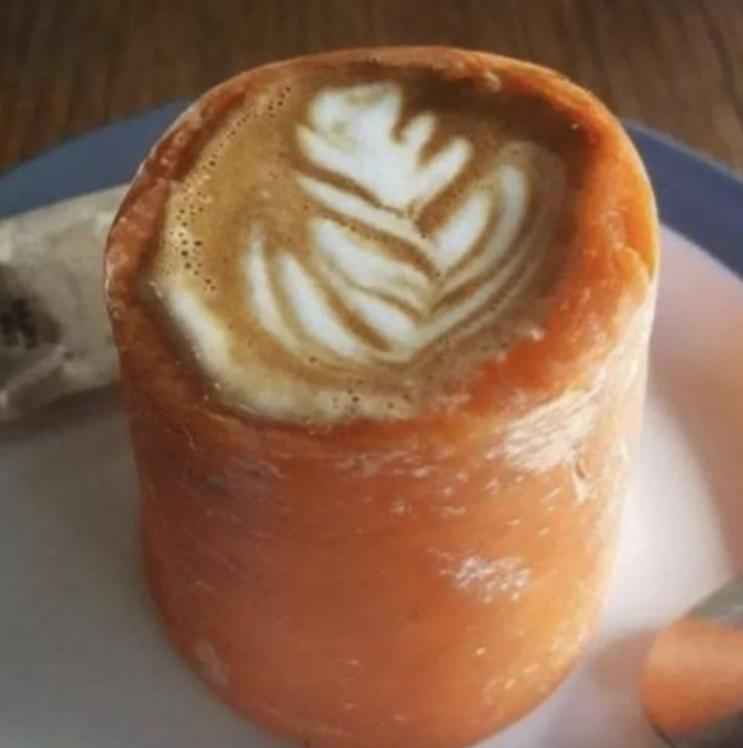 A latte with leaf art served in an edible carrot cup