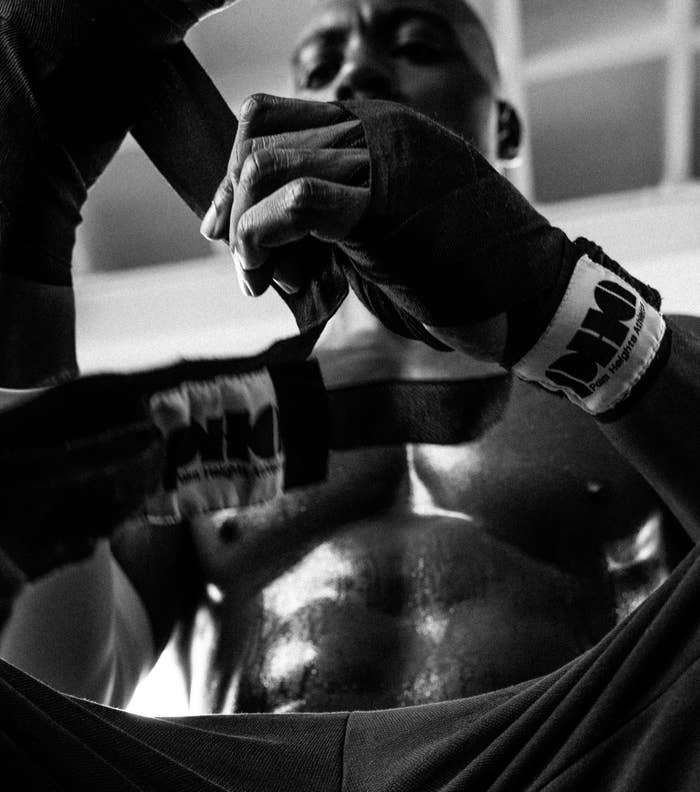 Boxer getting hands wrapped, focused expression, in a gym preparing for training or a match