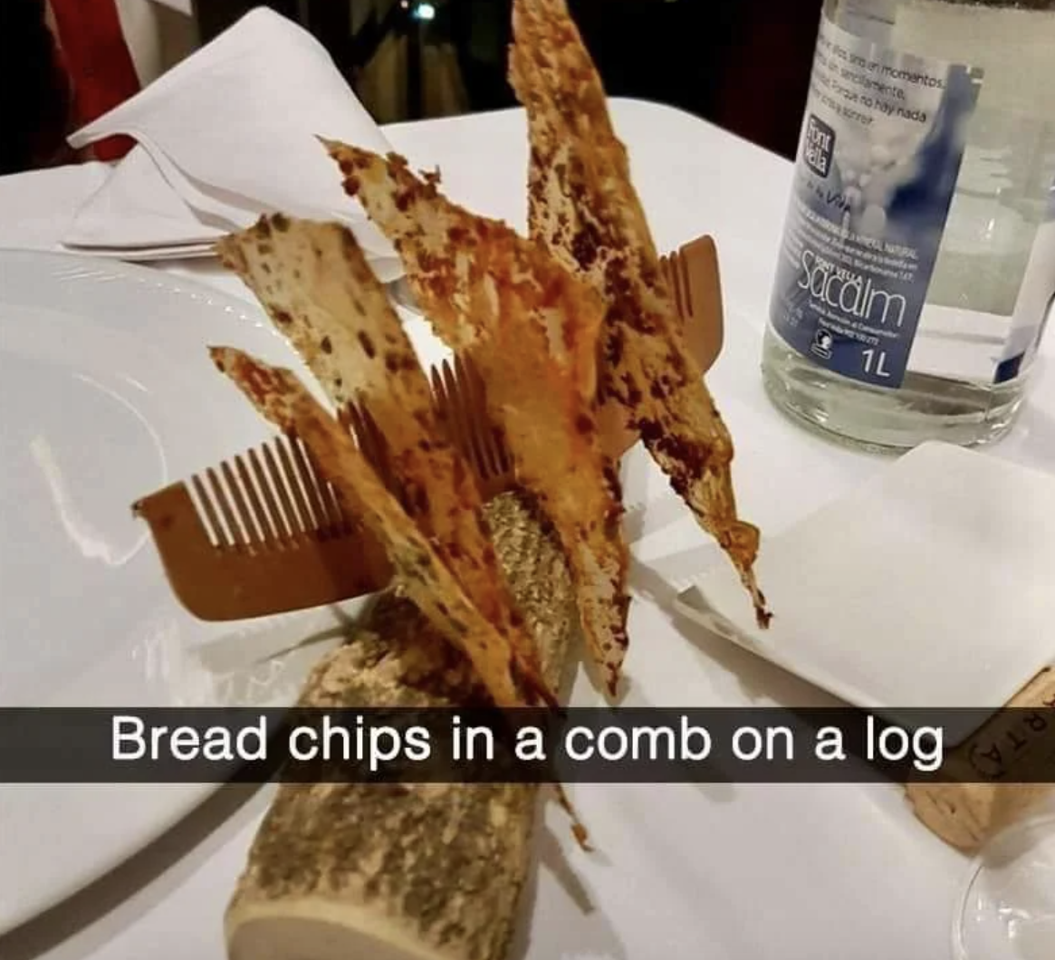 Bread chips creatively presented in a comb shape atop a wooden log at a dining table setting