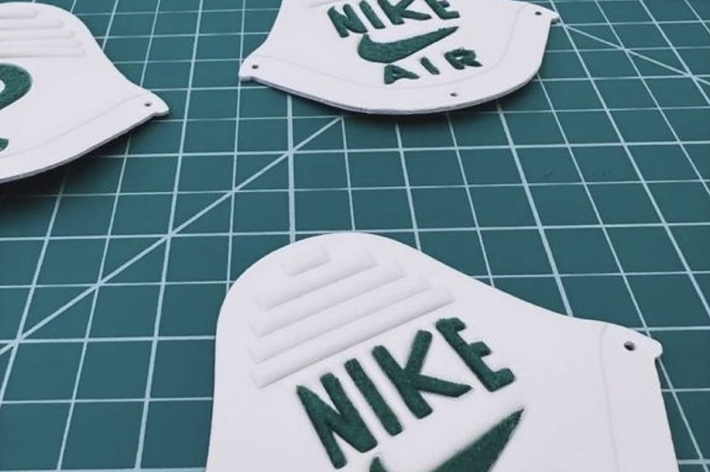 Nike Air sneaker tongue labels in various production stages on a textured surface