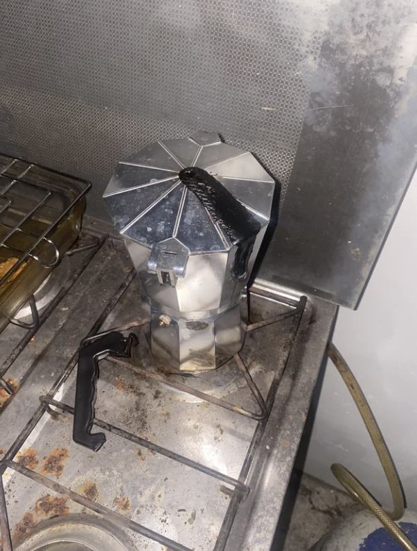 Moka pot on a stove, used and showing signs of wear, with no people in the image