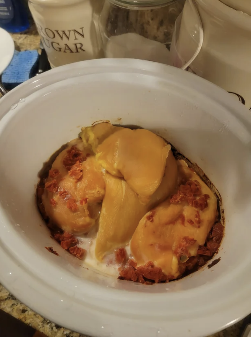 Baked sweet potatoes topped with melted cheese and bacon bits in a white slow cooker